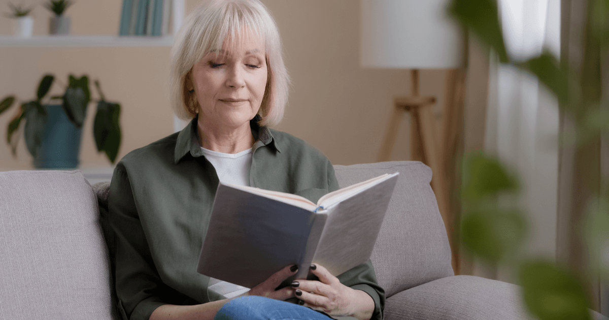 Alone Caucasian 50s lady Caucasian old woman mature lady senior grandmother professor teacher sitting on sofa resting studying education relaxing at home reading book enjoying literature learning